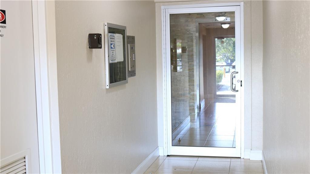 A hallway leads to a glass-paned door opening to an outdoor area with tile flooring — 7300 NW 17th Street # 202, Plantation FL 33313, PLANTATION, FL