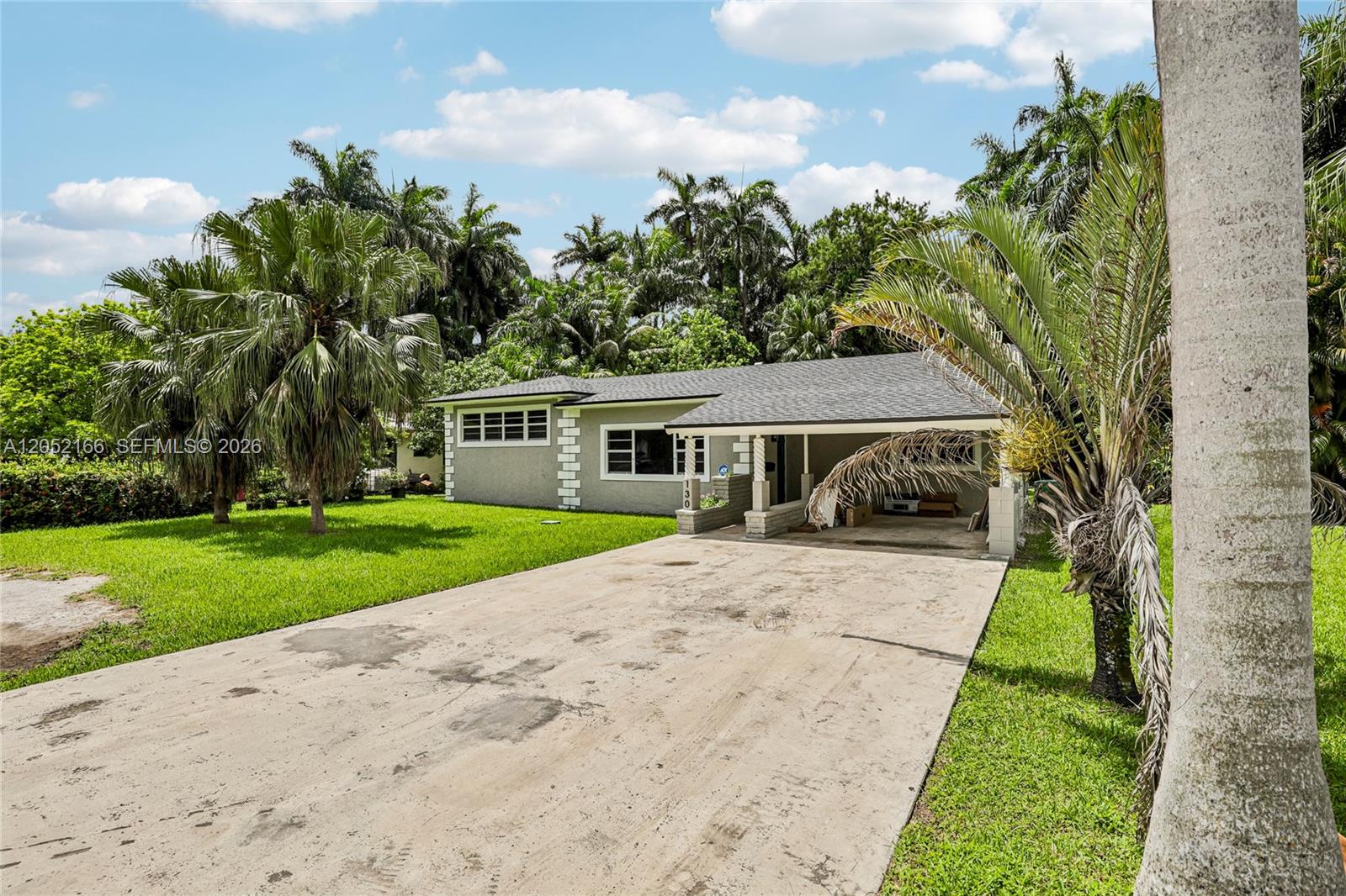 A single-story house with a concrete driveway, a carport, and surrounding palm trees — 130 NW 85th St, Miami FL 33150, MIAMI, FL