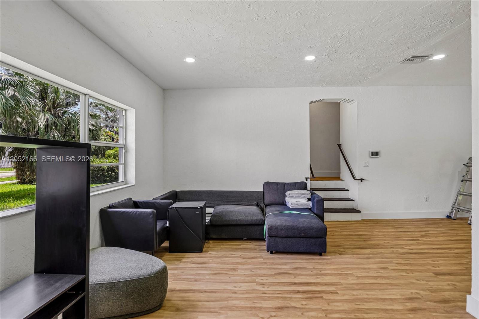 A living room features light wood flooring, white walls, a sectional sofa, and a staircase — 130 NW 85th St, Miami FL 33150, MIAMI, FL