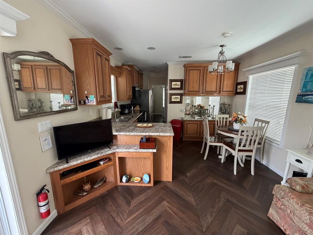 A kitchen and dining area with wood cabinets, granite countertops, and herringbone-patterned flooring — 2414 LIMEWOOD AVENUE, CLERMONT, FL