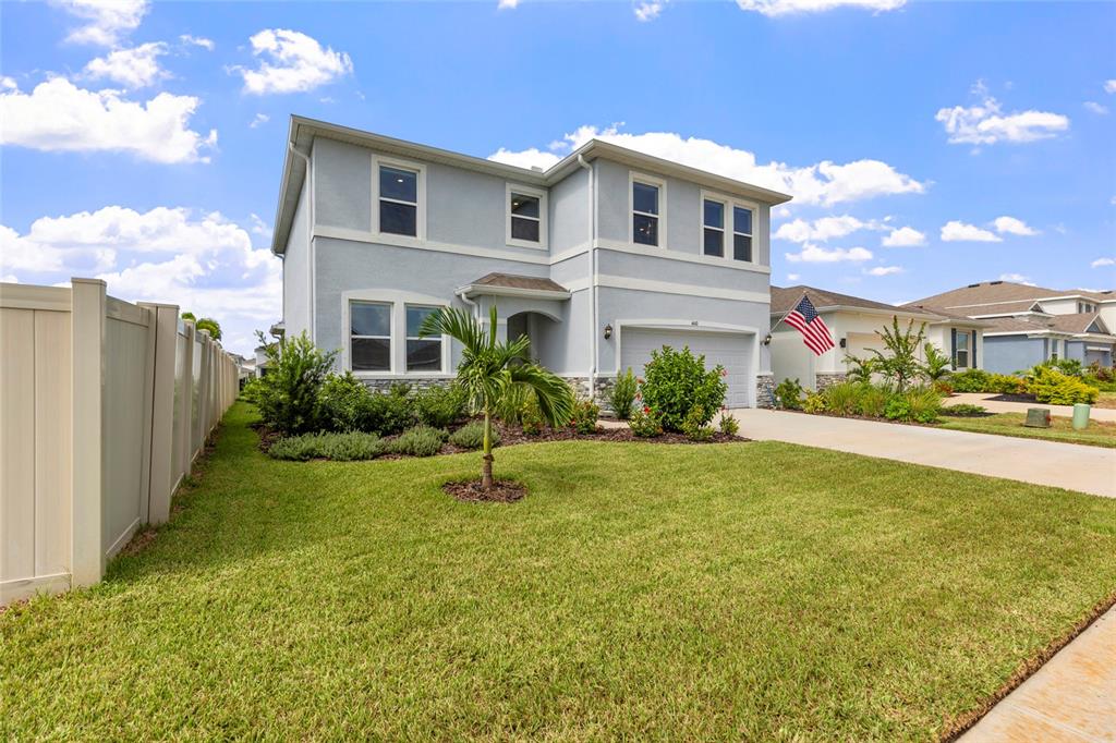 A two-story light blue house with a stone facade, a garage, and a front lawn — 4410 DUSKY DAWN LANE, PALMETTO, FL