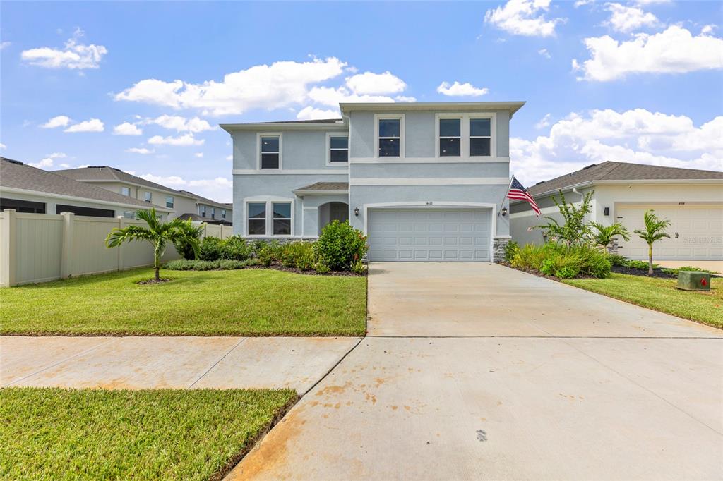 A two-story light blue house features a two-car garage and a landscaped front yard — 4410 DUSKY DAWN LANE, PALMETTO, FL