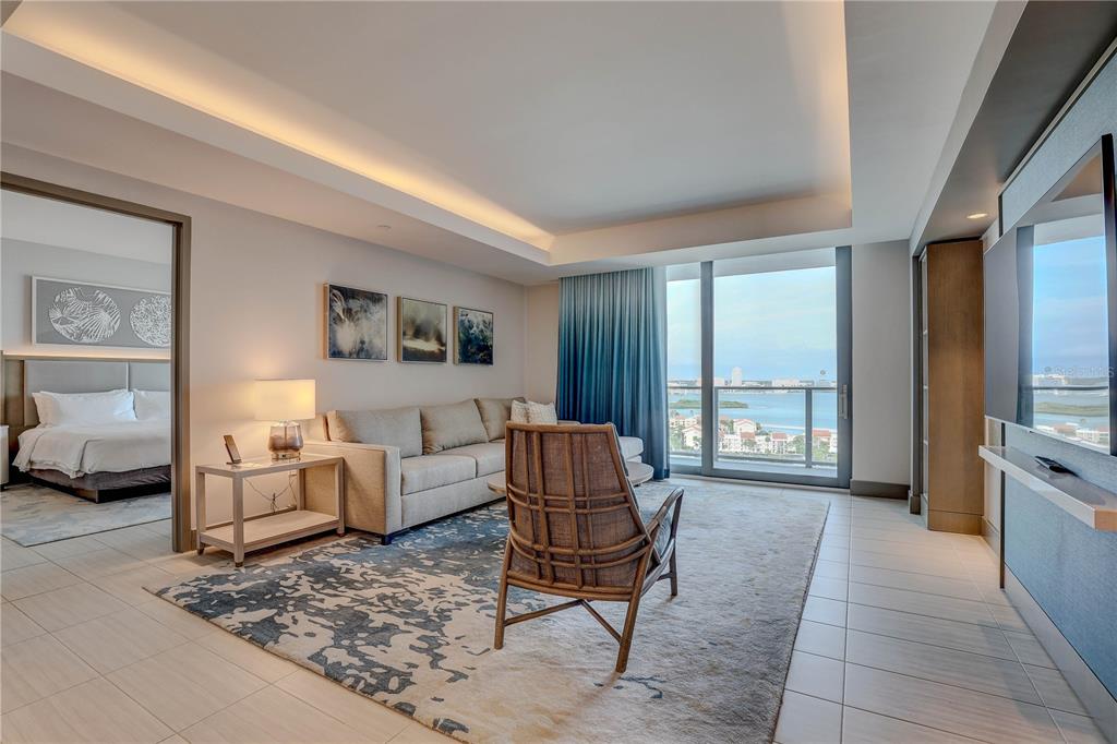 A modern living room features a sofa, accent chair, area rug, and a balcony view — 691 S GULFVIEW BOULEVARD UNIT 1608, CLEARWATER BEACH, FL