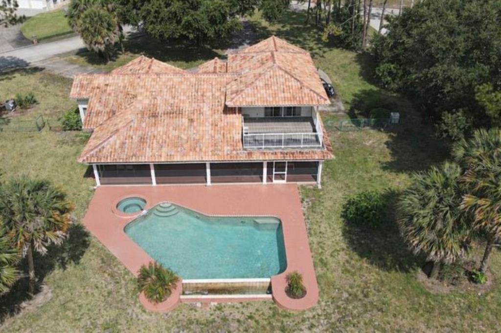 An aerial view of a house with a tile roof, a screened porch, and a pool — 12624 LAKE DENISE BOULEVARD, CLERMONT, FL