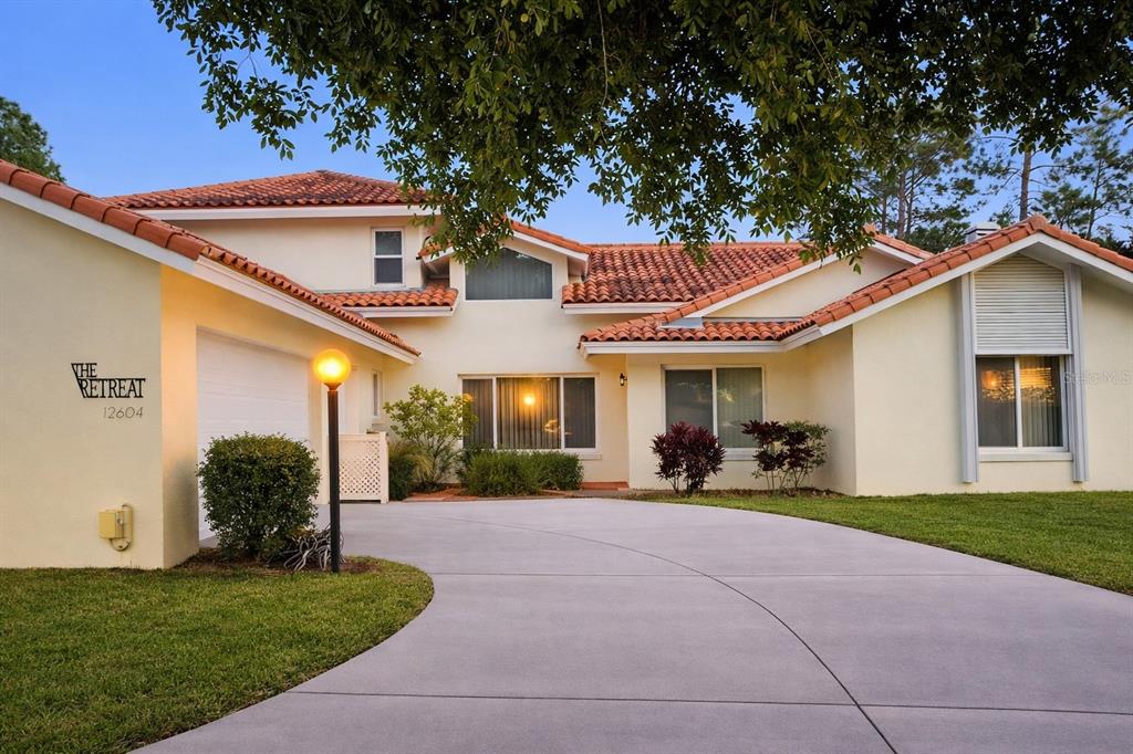A two-story house with a tile roof, light-colored stucco walls, and a concrete driveway — 12624 LAKE DENISE BOULEVARD, CLERMONT, FL