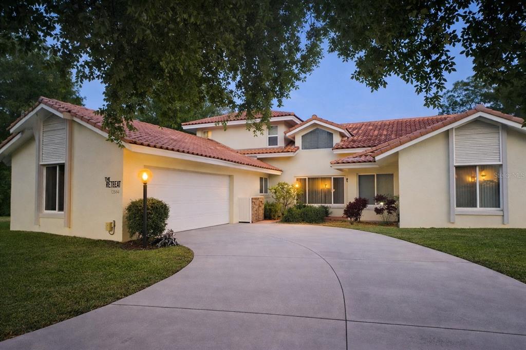 A single-story house with a tile roof, white stucco exterior, and a concrete driveway — 12624 LAKE DENISE BOULEVARD, CLERMONT, FL