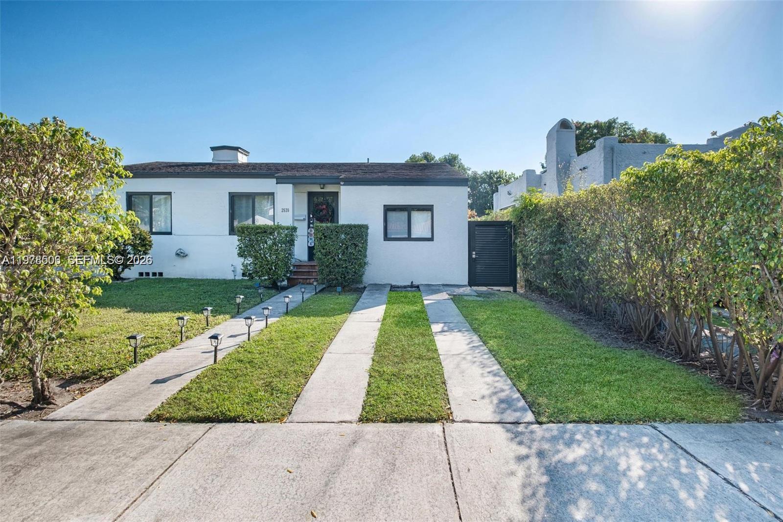 A single-story white house features a front lawn, a concrete driveway, and a hedge — 2520 SW 20th St # 1, Miami FL 33145, MIAMI, FL