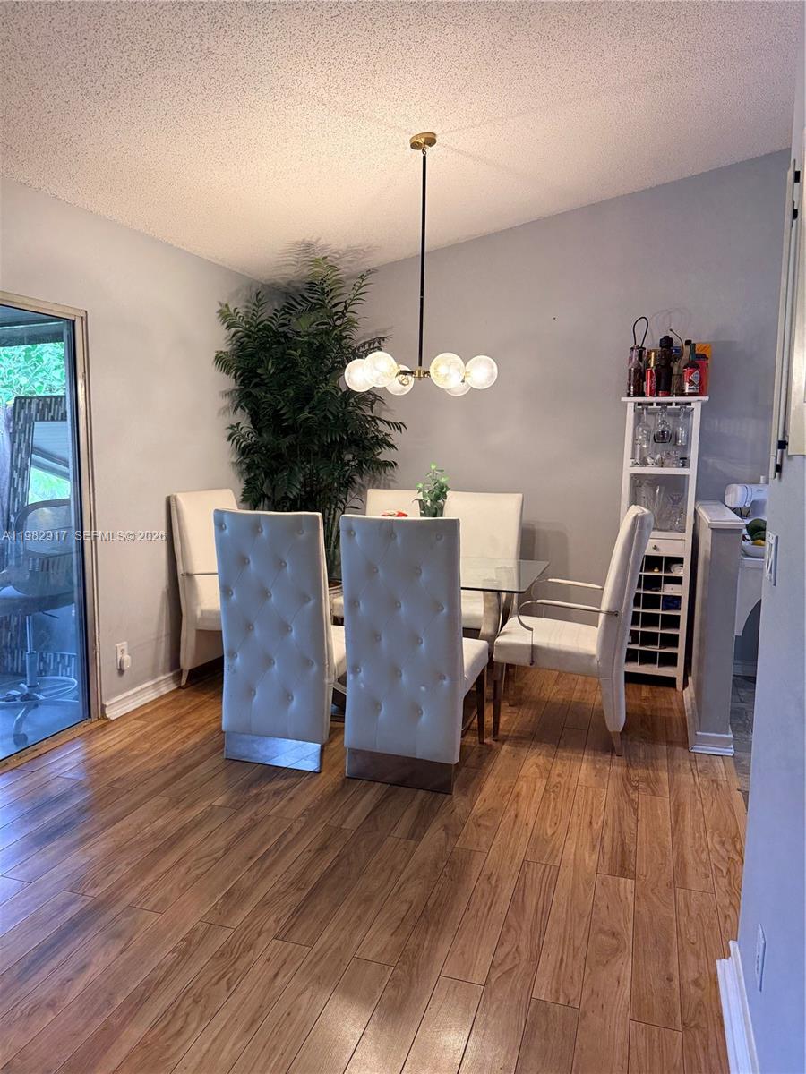 A dining room features a glass table, four tufted chairs, a chandelier, and a plant — 9963 Baywater Dr, Boca Raton FL 33496, BOCA RATON, FL