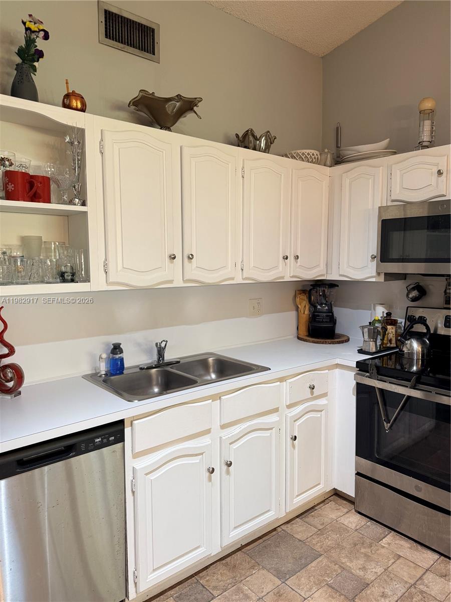 A kitchen features white cabinets, stainless steel appliances, a double sink, and tiled flooring — 9963 Baywater Dr, Boca Raton FL 33496, BOCA RATON, FL