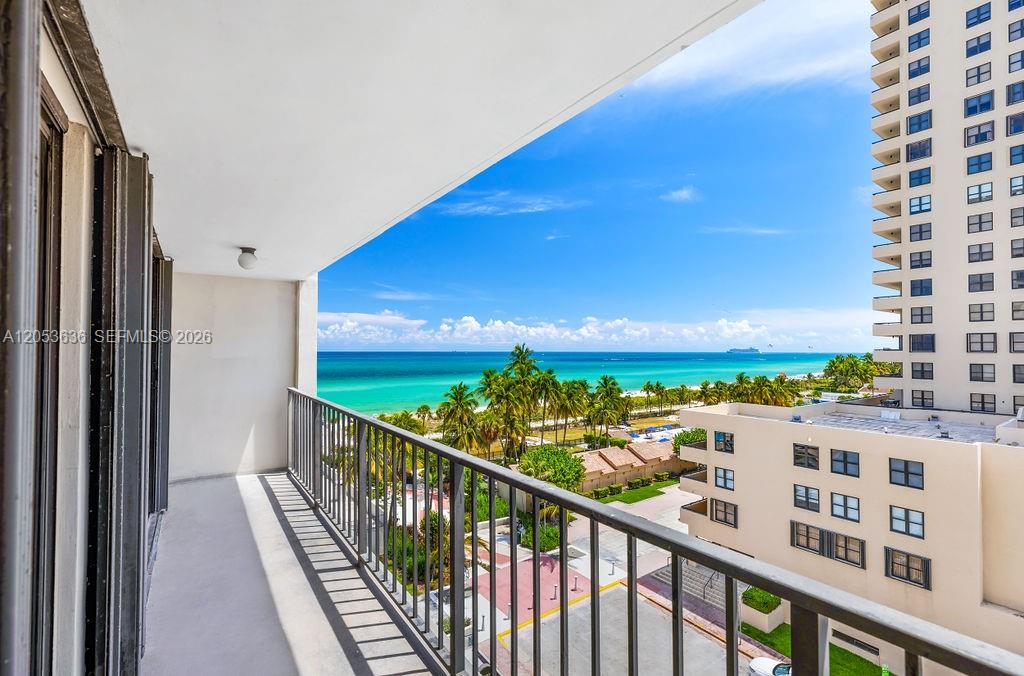 A balcony overlooks a beach, palm trees, and a neighboring high-rise building — 2625 Collins Ave # 702, Miami Beach FL 33140, MIAMI BEACH, FL