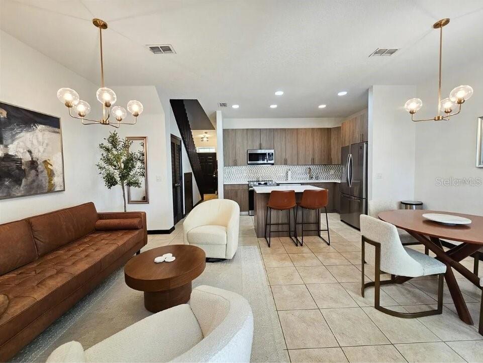 A kitchen features wood-tone cabinets, stainless steel appliances, a center island, and tiled flooring — 2311 CARAVELLE CIRCLE, KISSIMMEE, FL