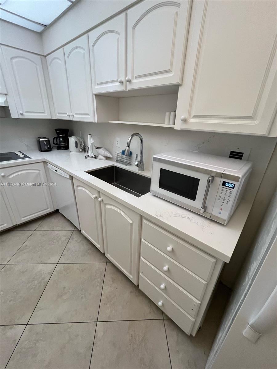 A white kitchen features light-colored cabinetry, a stainless steel sink, and a countertop microwave — 3901 S S Ocean dr, Hollywood FL 33019, HOLLYWOOD, FL