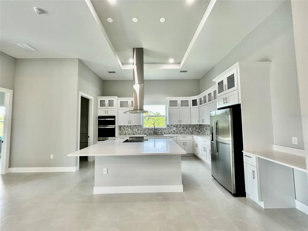 A modern kitchen features white cabinetry, a large center island, and stainless steel appliances — 8147 TRACY CIRCLE, PORT CHARLOTTE, FL