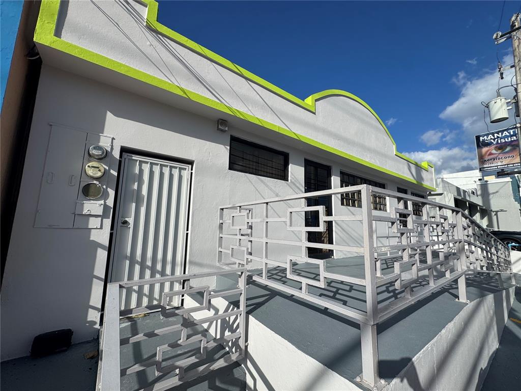 A white building exterior features a lime green trim, a metal railing, and a ramp — MARGINAL ELIOT VELEZ ST. ATENAS UNIT J-14, MANATI, PR