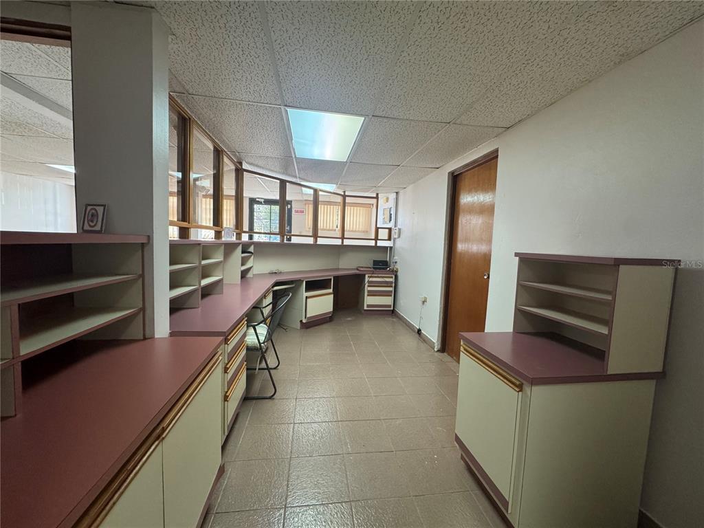 An office space features built-in desks, shelving units, tile flooring, and a drop ceiling — MARGINAL ELIOT VELEZ ST. ATENAS UNIT J-14, MANATI, PR