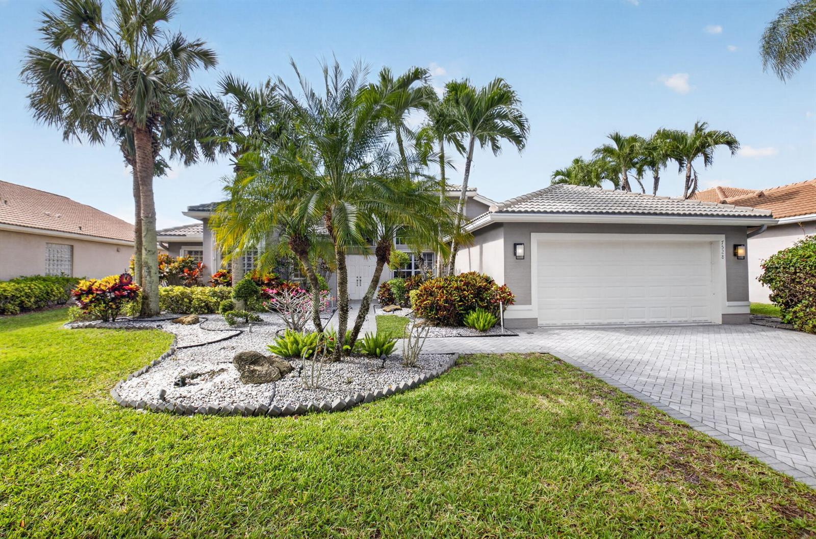 A single-story house with a white garage, a paved driveway, and a landscaped front yard — 7528 Tarpon Cove Circle, Lake Worth FL 33467, LAKE WORTH, FL