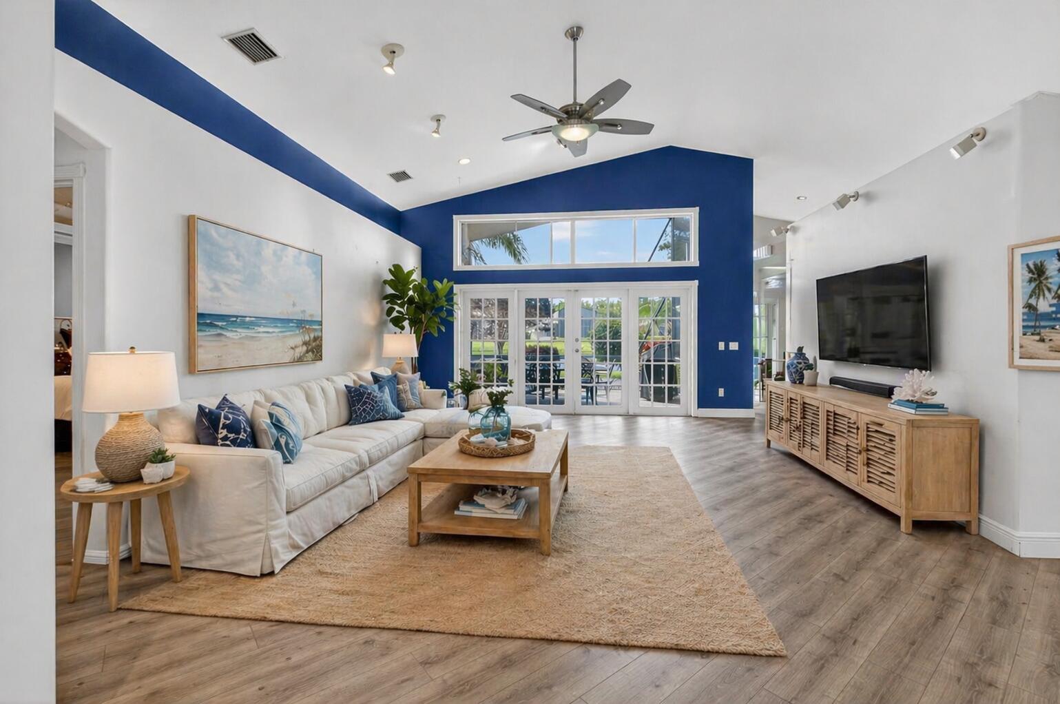 A living room features a white sectional sofa, blue accent wall, and wood-look flooring — 7528 Tarpon Cove Circle, Lake Worth FL 33467, LAKE WORTH, FL