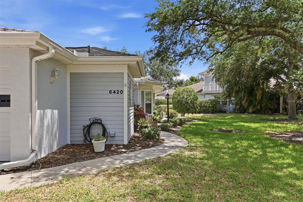A light blue house exterior with a concrete walkway and a large tree nearby — 6420 CARRINGTON CIRCLE UNIT 35, SARASOTA, FL
