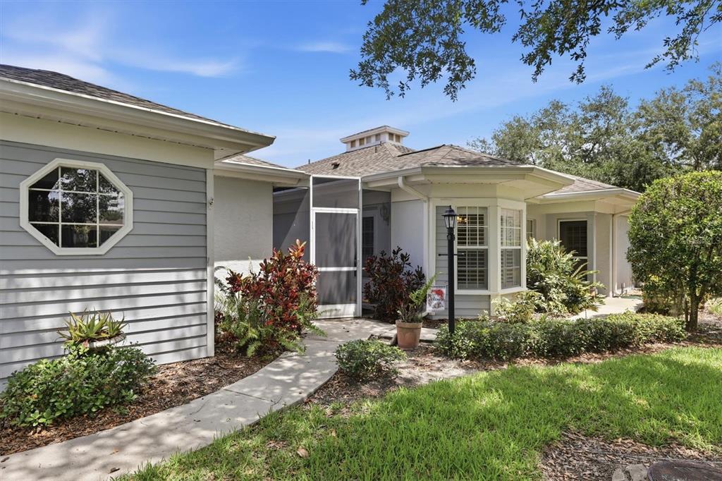 The exterior of a house features gray siding, a screened entryway, and a bay window — 6420 CARRINGTON CIRCLE UNIT 35, SARASOTA, FL