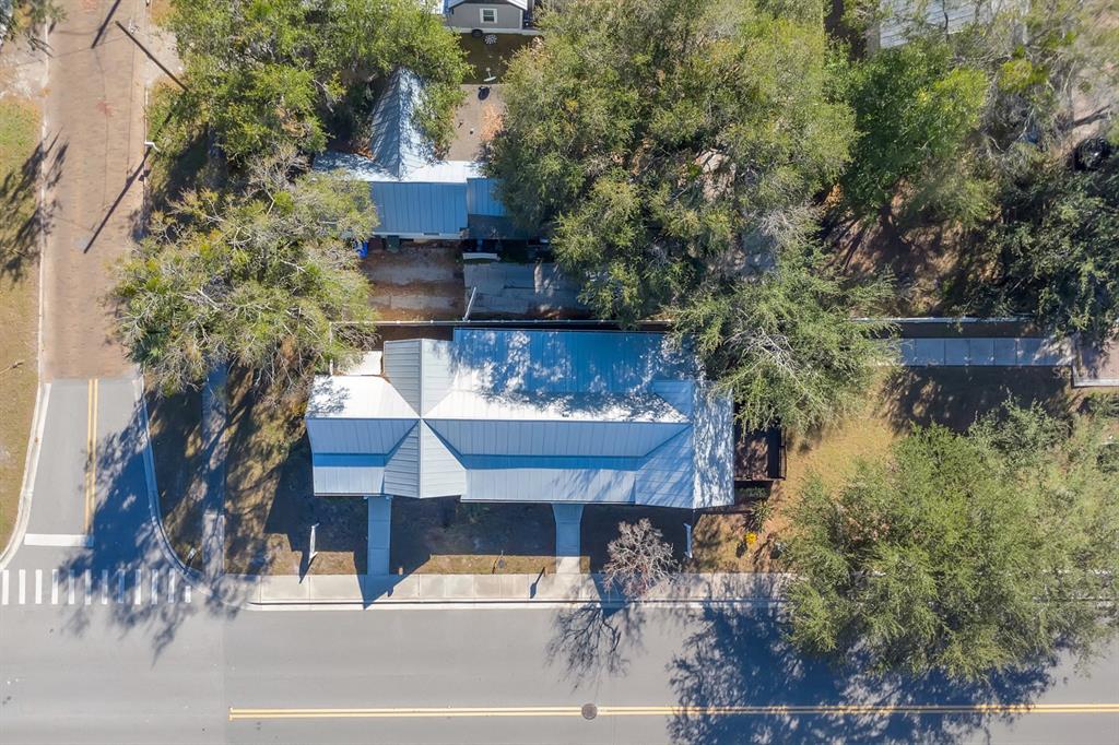An aerial view shows a house with a metal roof surrounded by trees and sidewalks — 702 MABBETTE STREET, KISSIMMEE, FL
