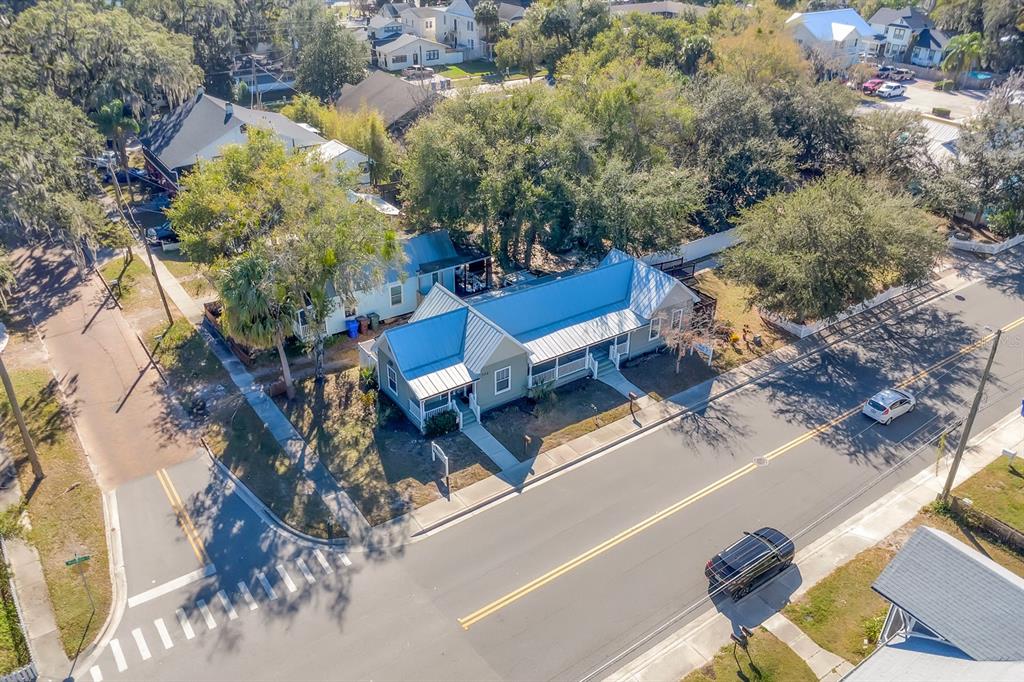 An aerial view shows a light-colored house with a blue metal roof on a corner lot — 702 MABBETTE STREET, KISSIMMEE, FL