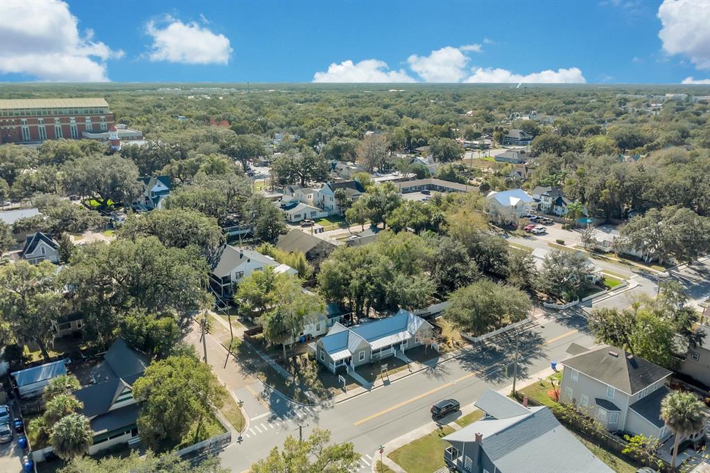 An aerial view shows a residential street with houses, trees, and a large building nearby — 702 MABBETTE STREET, KISSIMMEE, FL