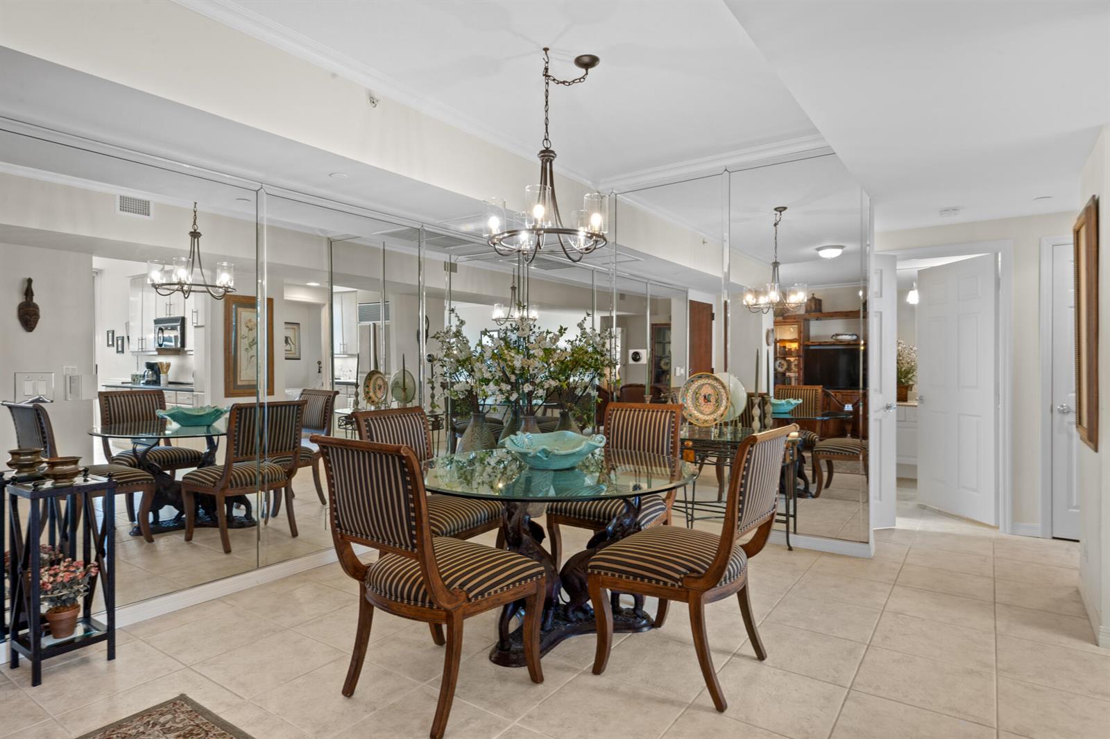 A dining room features a glass-topped table, striped chairs, a chandelier, and mirrored walls — 3200 N Ocean Boulevard # 1506, Fort Lauderdale FL 33308, FORT LAUDERDALE, FL