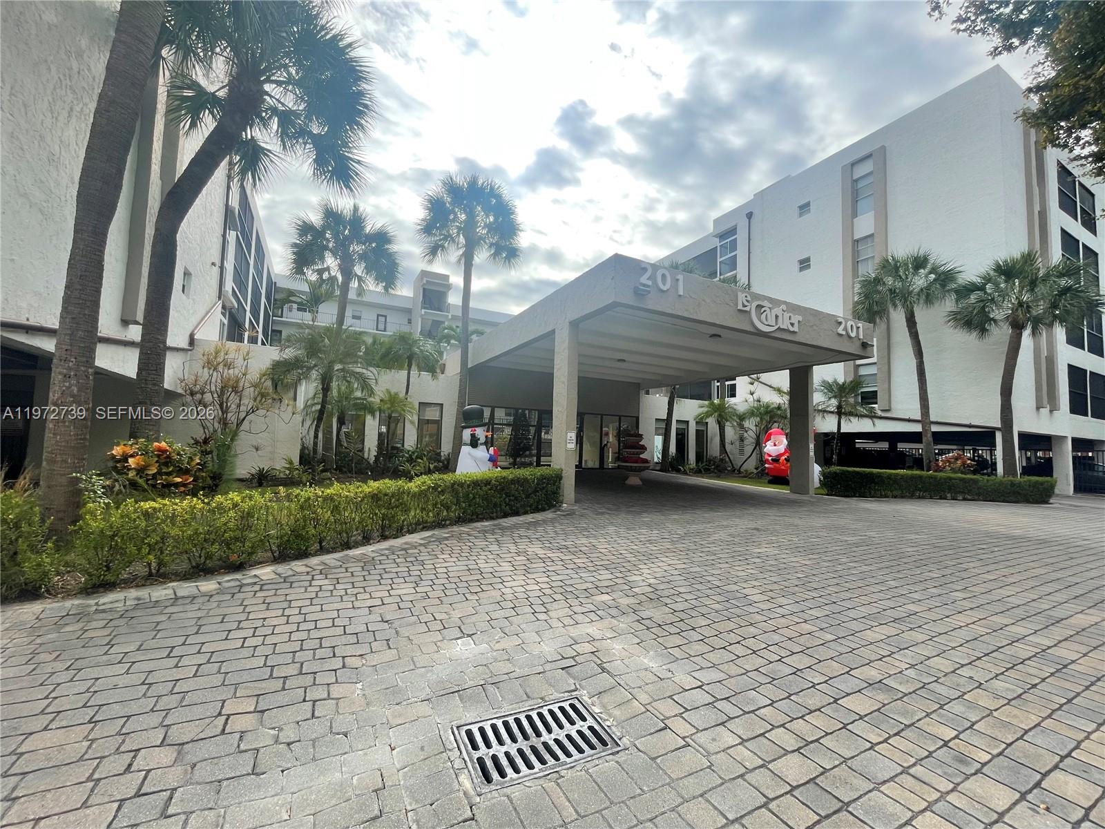The exterior of a multi-story apartment building features a covered entrance with palm trees — 201 178th Dr # 334, Sunny Isles Beach FL 33160, SUNNY ISLES BEACH, FL