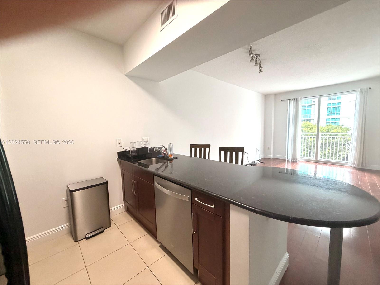 A kitchen with dark wood cabinets, a black countertop, and a stainless steel dishwasher — 7290 SW 90th St # 303, Miami FL 33156, MIAMI, FL