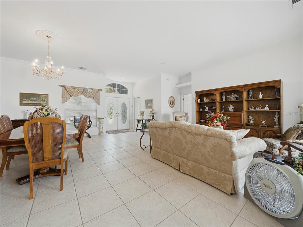 A dining area and living room with tile floors, a chandelier, and a wooden bookshelf — 118 W JULIANA WAY, AUBURNDALE, FL