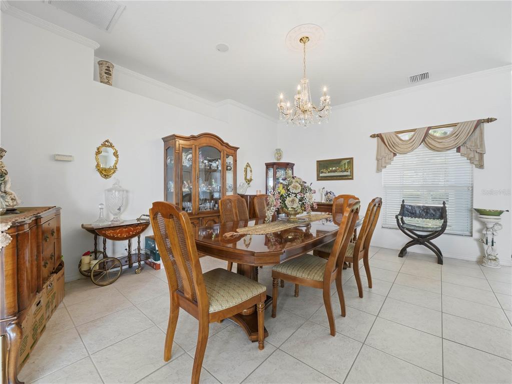 A formal dining room features a wooden table, matching chairs, a chandelier, and tile flooring — 118 W JULIANA WAY, AUBURNDALE, FL