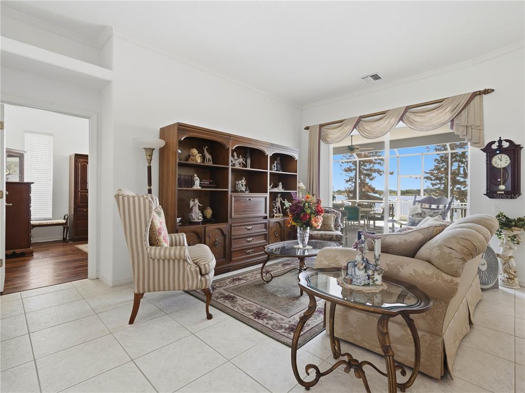 A living room features tile floors, a wooden wall unit, and a view of a lake — 118 W JULIANA WAY, AUBURNDALE, FL