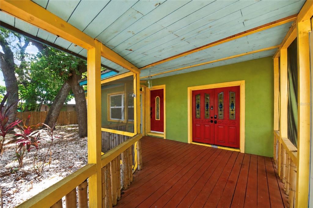 A covered wooden porch features a red double door, a red single door, and yellow trim — 6270 62ND AVENUE N, PINELLAS PARK, FL