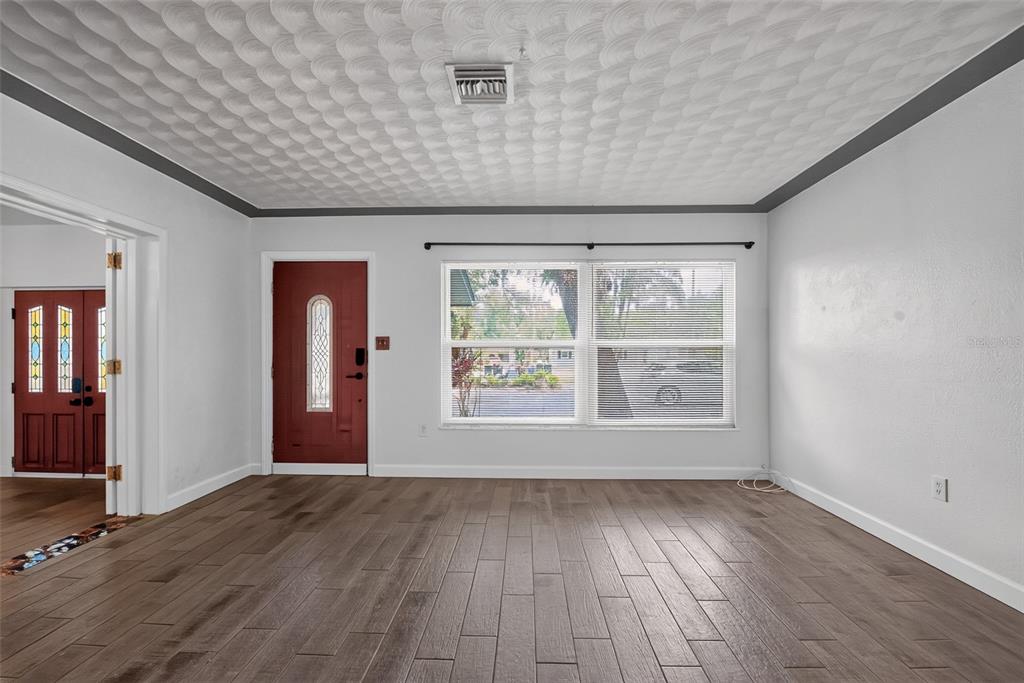 A living room features wood-look flooring, a red front door, and a textured ceiling — 6270 62ND AVENUE N, PINELLAS PARK, FL
