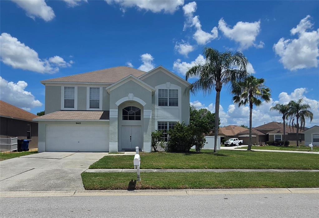 A two-story suburban house with a white garage, arched entryway, and palm trees in front — 10422 GLEN WILLOW LANE, TAMPA, FL