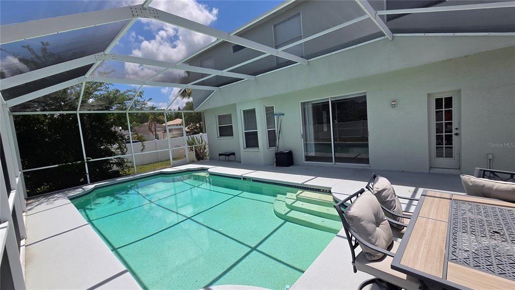 A screened-in patio features a swimming pool with steps and outdoor furniture — 10422 GLEN WILLOW LANE, TAMPA, FL