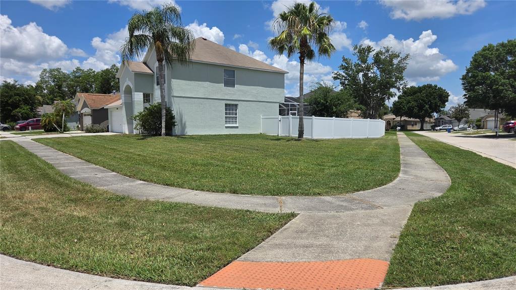 A two-story house with a light green exterior sits on a corner lot with sidewalks — 10422 GLEN WILLOW LANE, TAMPA, FL