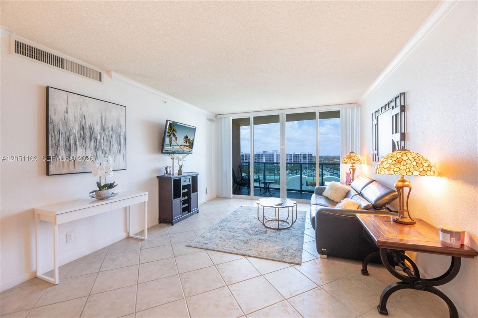 A living room features tile floors, a dark leather sofa, and a balcony with views — 2501 S Ocean Dr # 828, Hollywood FL 33019, HOLLYWOOD, FL