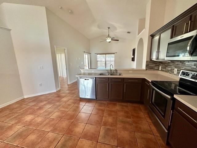 A kitchen with dark cabinets, stainless steel appliances, and tile flooring opens to a living area — 4627 EAGLET LANE, KISSIMMEE, FL