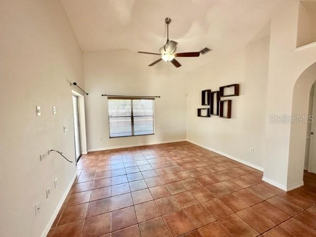 A living room with vaulted ceilings, a ceiling fan, and brown tile flooring — 4627 EAGLET LANE, KISSIMMEE, FL