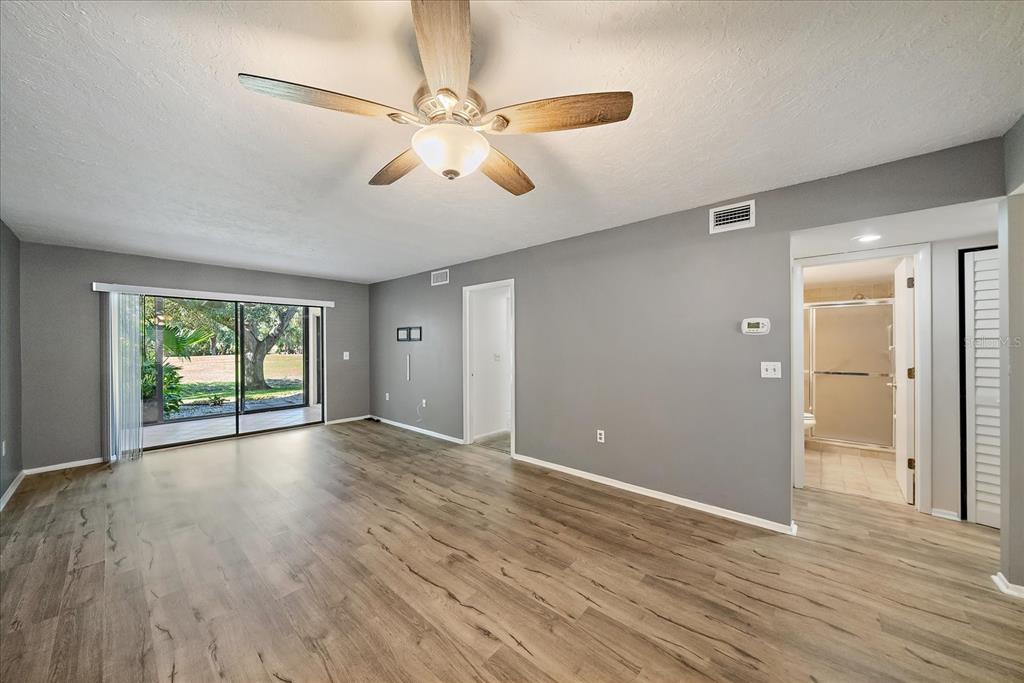 A living room with gray walls, wood-look flooring, a ceiling fan, and a sliding glass door — 7742 EAGLE CREEK DRIVE UNIT 7524, SARASOTA, FL