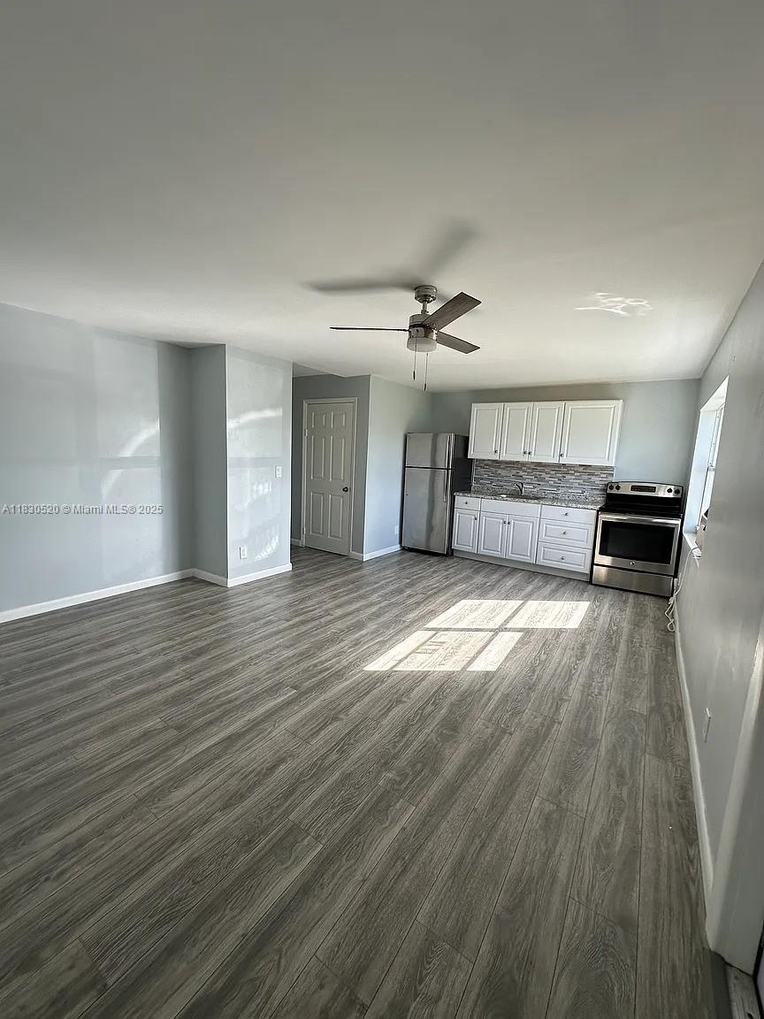 A kitchen and living area feature light gray walls, wood-look flooring, and white cabinetry — 4410 26th Ave # 2, Vero Beach FL 32967, VERO BEACH, FL