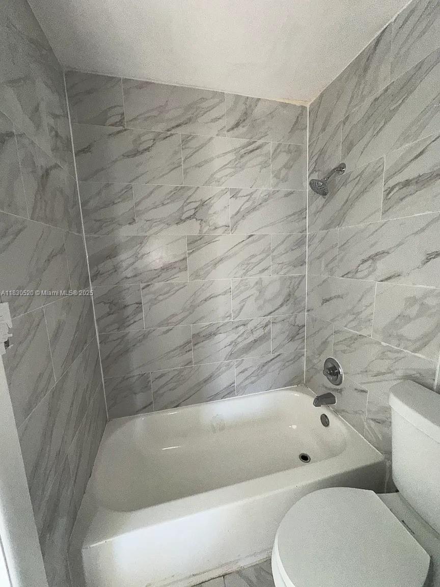 A bathroom features a white bathtub and shower surround tiled with gray and white marble — 4410 26th Ave # 2, Vero Beach FL 32967, VERO BEACH, FL