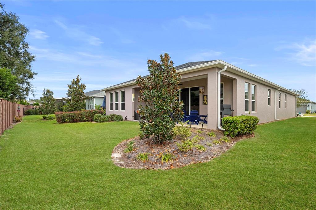 The exterior of a beige house features a covered patio, a landscaped yard, and fencing — 4252 NW 55TH TERRACE, OCALA, FL