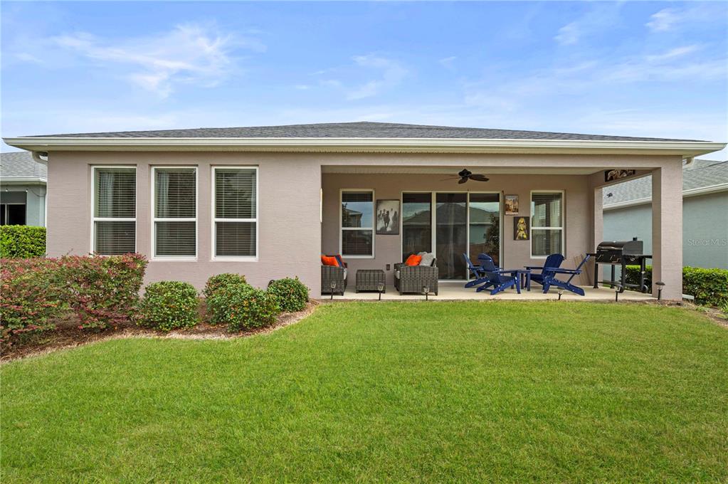 A rear view of a single-story house with a covered patio and a grassy yard — 4252 NW 55TH TERRACE, OCALA, FL