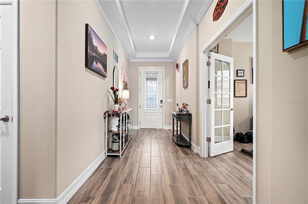 A bright entryway features wood-look tile flooring, a tray ceiling, and a white front door — 4252 NW 55TH TERRACE, OCALA, FL