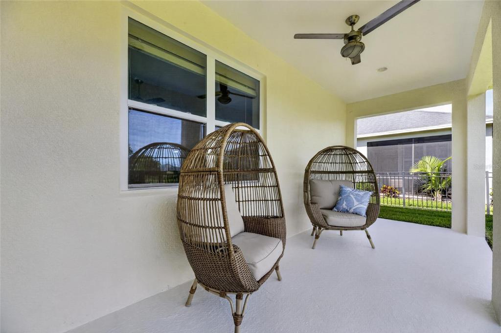 A covered patio features two wicker egg chairs, a ceiling fan, and a view of grass — 7328 MILESTONE DRIVE, APOLLO BEACH, FL