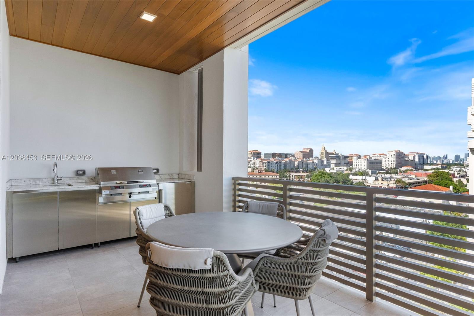 A balcony features a stainless steel outdoor kitchen, a round table, and city views — 515 Valencia Ave # 802, Coral Gables FL 33134, CORAL GABLES, FL