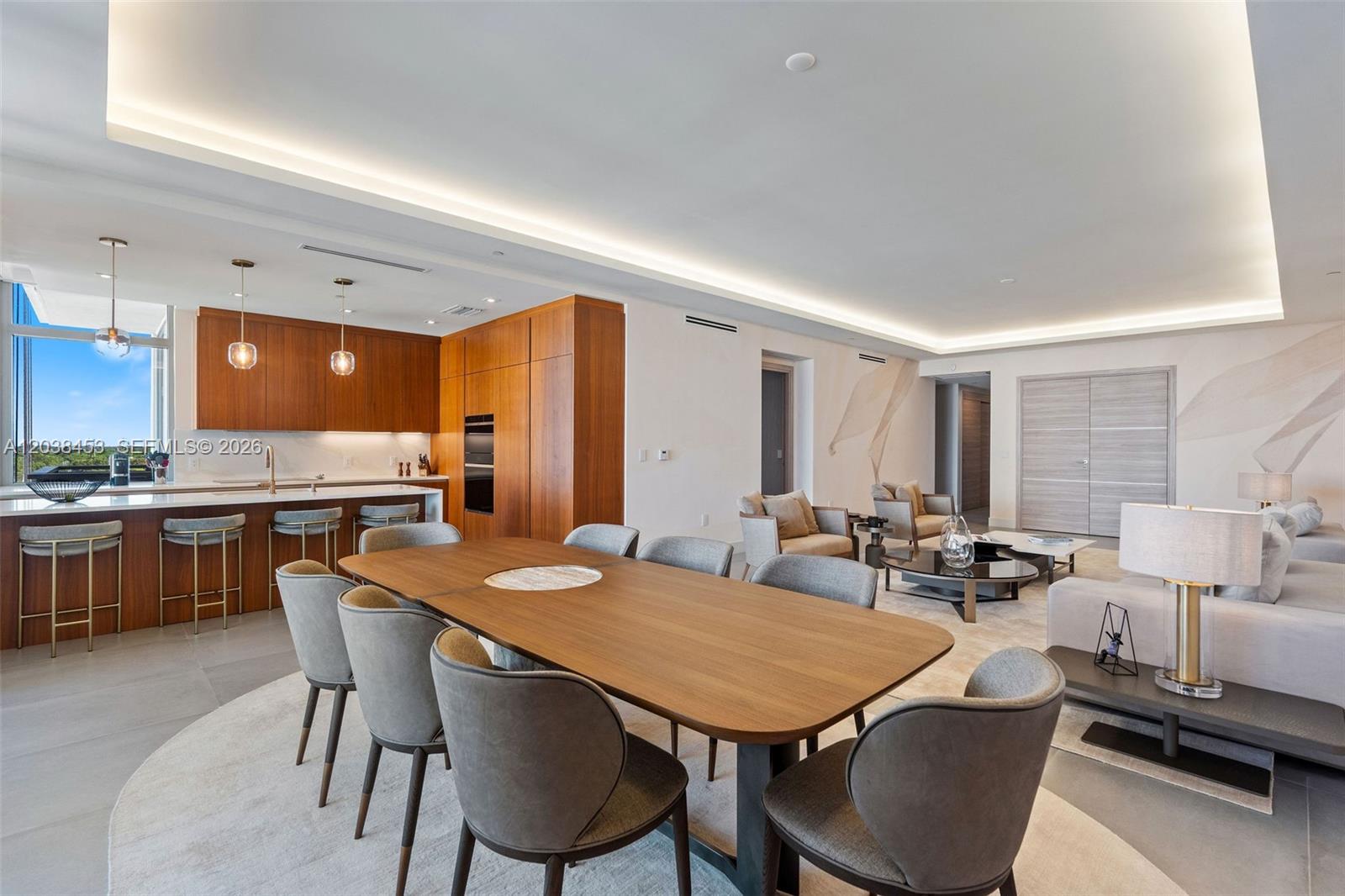 A modern open-concept living and dining area features wood cabinetry, a kitchen island, and seating — 515 Valencia Ave # 802, Coral Gables FL 33134, CORAL GABLES, FL