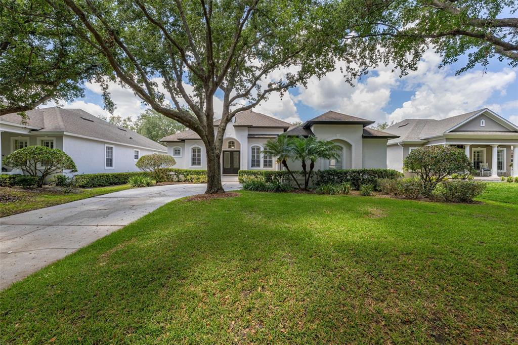 A single-story house with a concrete driveway, large shade tree, and manicured lawn — 8351 BOWDEN WAY, WINDERMERE, FL
